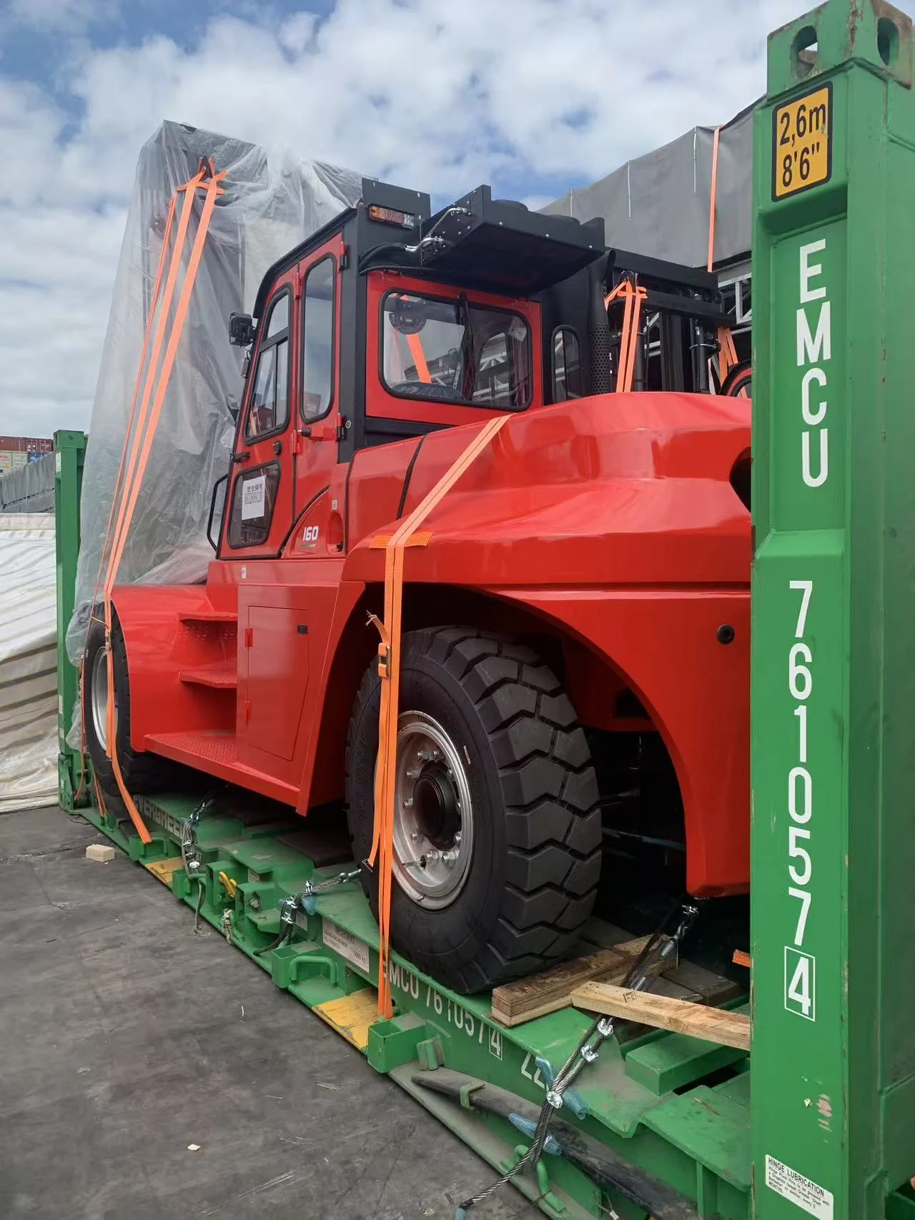 Side view of a heavy forklift on a 20-foot flat rack