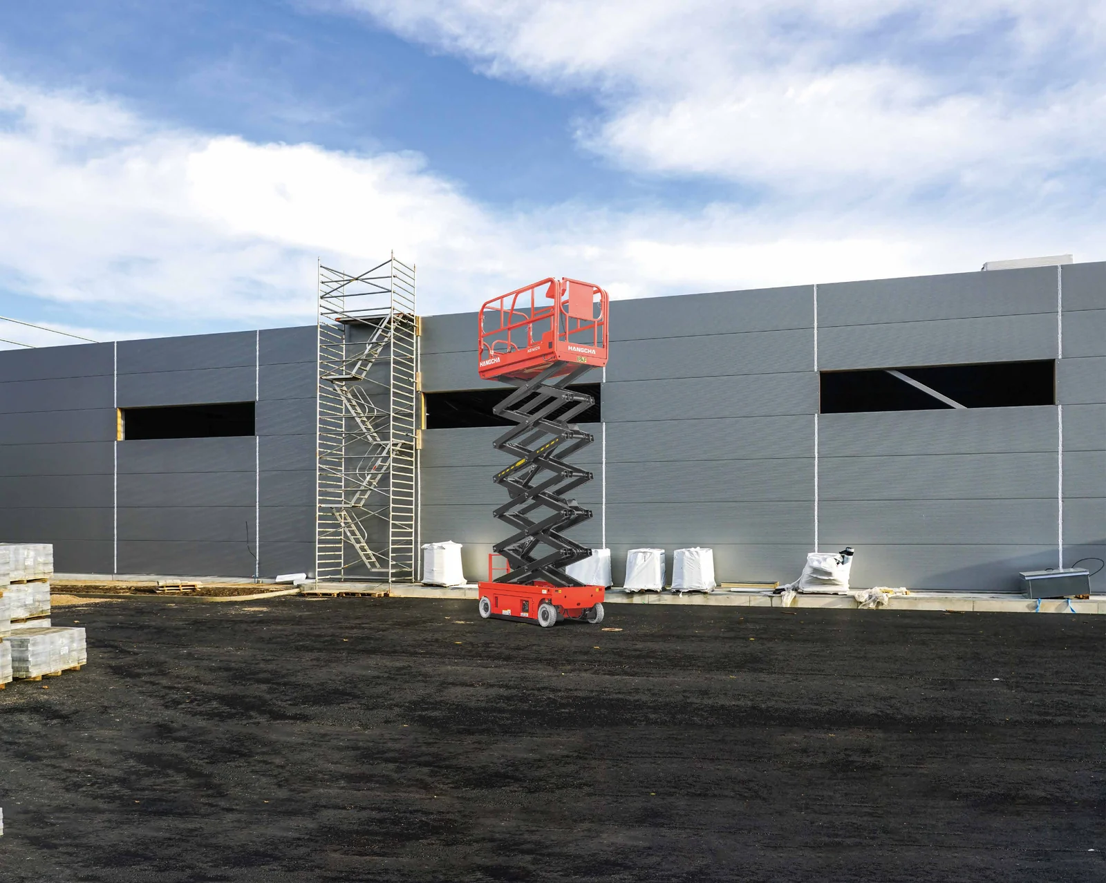 Hangcha HS E-Drive scissor lift raised beside an industrial building